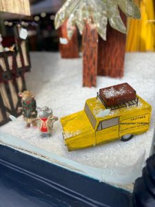 Two mice are standing next to a yellow three wheeler van with the name Trotters on the side.